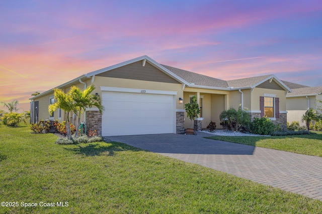 single story home featuring stone siding, an attached garage, decorative driveway, and a front lawn