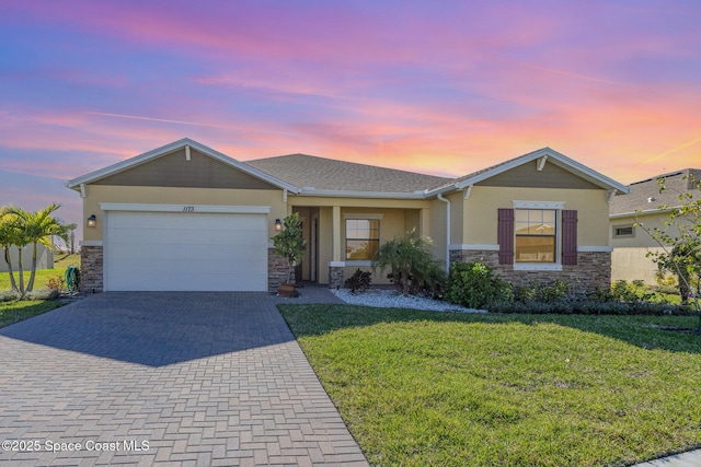 ranch-style home with stucco siding, a lawn, decorative driveway, stone siding, and a garage