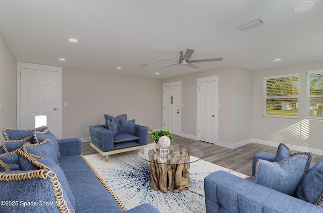 living room featuring baseboards, a textured ceiling, visible vents, and wood finished floors