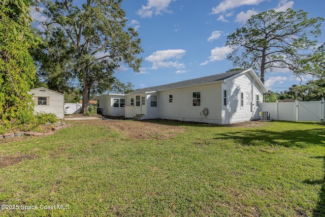 rear view of property featuring a fenced backyard, a gate, a lawn, and an outdoor structure