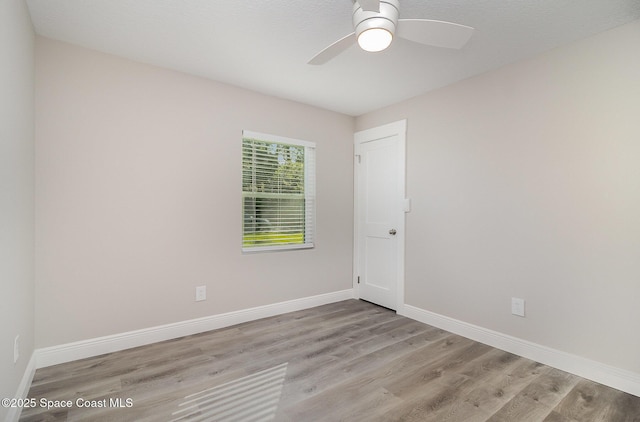 spare room featuring a ceiling fan, baseboards, and wood finished floors