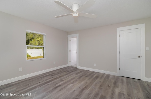 spare room with ceiling fan, a textured ceiling, baseboards, and wood finished floors