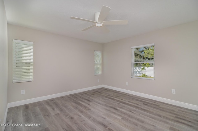 spare room featuring ceiling fan, baseboards, and wood finished floors