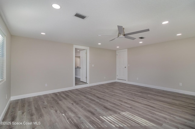 spare room with wood finished floors, visible vents, and baseboards