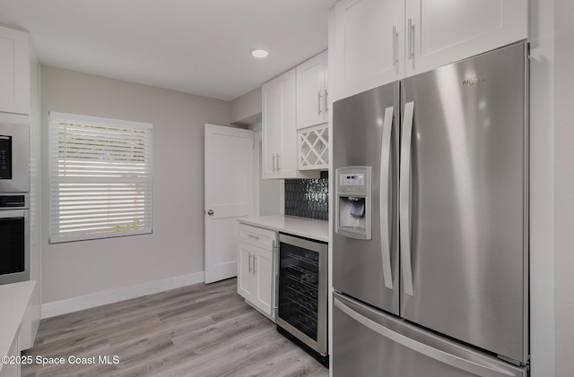 kitchen featuring stainless steel appliances, wine cooler, light countertops, and white cabinets