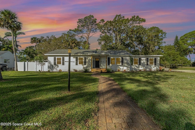 ranch-style house featuring fence and a yard