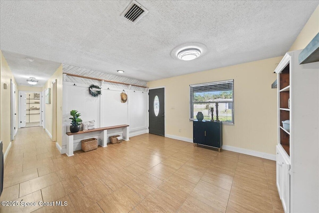 foyer with baseboards, visible vents, and a textured ceiling