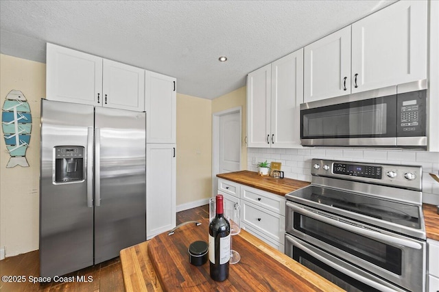 kitchen with dark wood finished floors, butcher block countertops, stainless steel appliances, white cabinetry, and tasteful backsplash