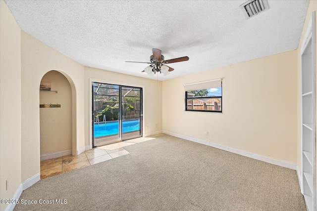 carpeted spare room with baseboards, visible vents, a textured ceiling, and a ceiling fan