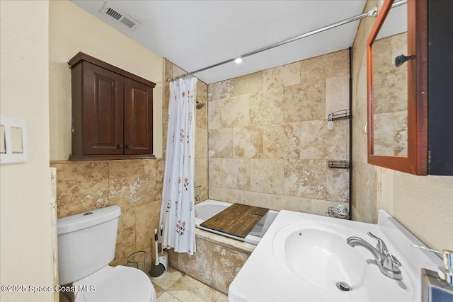 full bathroom with visible vents, a sink, toilet, tile walls, and shower / bathtub combination with curtain