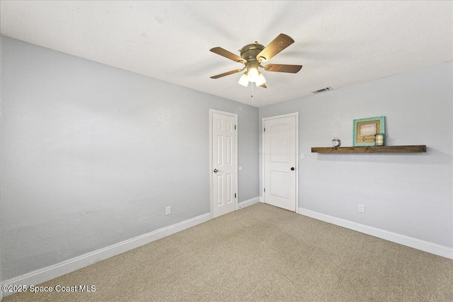 carpeted empty room featuring visible vents, baseboards, a textured ceiling, and a ceiling fan