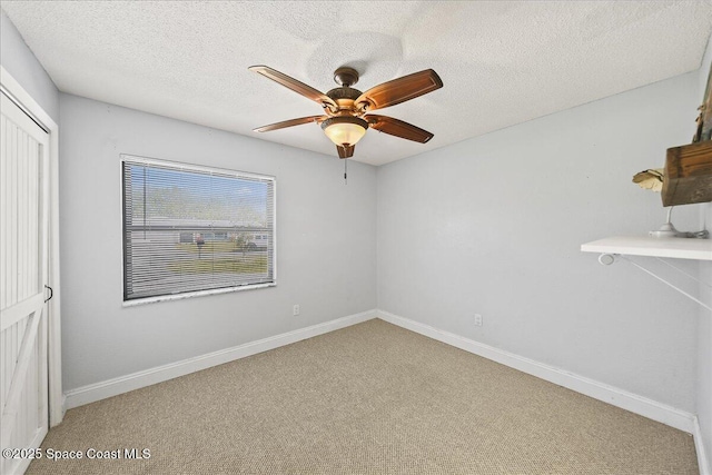 spare room with ceiling fan, carpet flooring, baseboards, and a textured ceiling