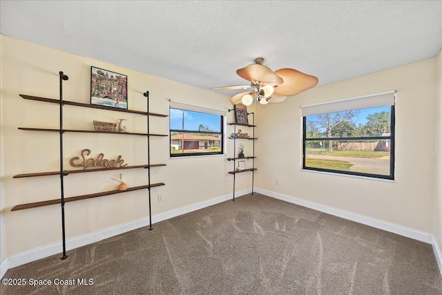 carpeted spare room featuring a ceiling fan, baseboards, and a textured ceiling