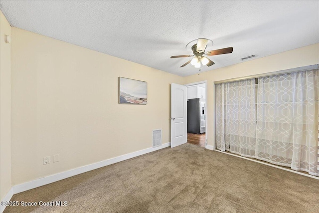 unfurnished bedroom with visible vents, baseboards, a textured ceiling, and stainless steel refrigerator with ice dispenser