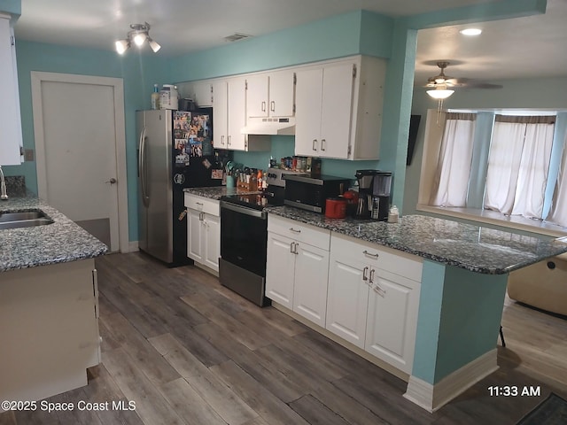 kitchen featuring under cabinet range hood, dark wood-style flooring, white cabinets, appliances with stainless steel finishes, and dark stone countertops