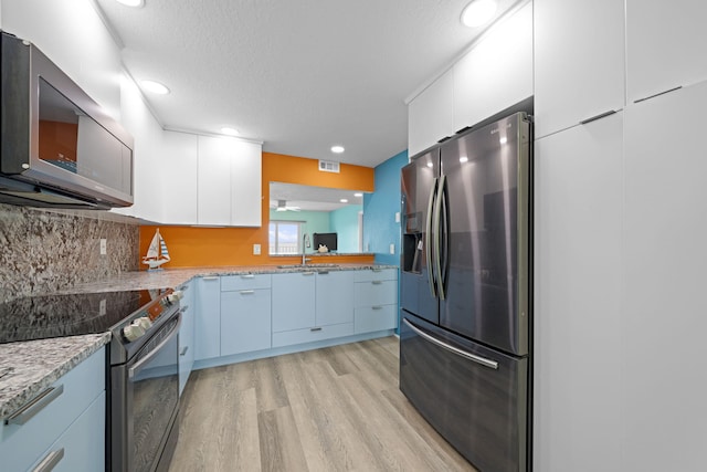 kitchen with visible vents, stainless steel appliances, light wood-type flooring, white cabinetry, and a sink