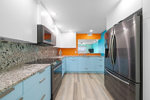 kitchen featuring stainless steel appliances, light stone counters, light wood-type flooring, and white cabinetry