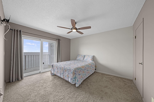 bedroom with access to exterior, ceiling fan, a textured ceiling, and carpet flooring