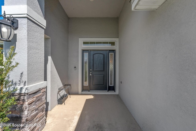 view of exterior entry featuring visible vents and stucco siding