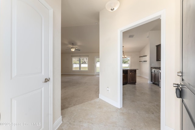 corridor with light tile patterned floors, light carpet, visible vents, baseboards, and an inviting chandelier