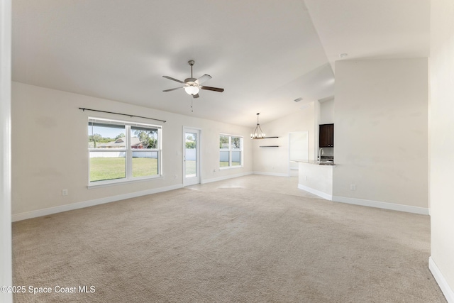 unfurnished living room featuring light carpet, vaulted ceiling, ceiling fan with notable chandelier, and baseboards