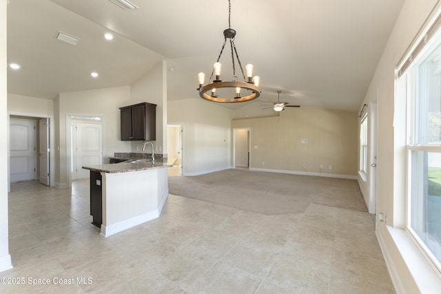 kitchen featuring pendant lighting, lofted ceiling, a sink, dark brown cabinetry, and baseboards