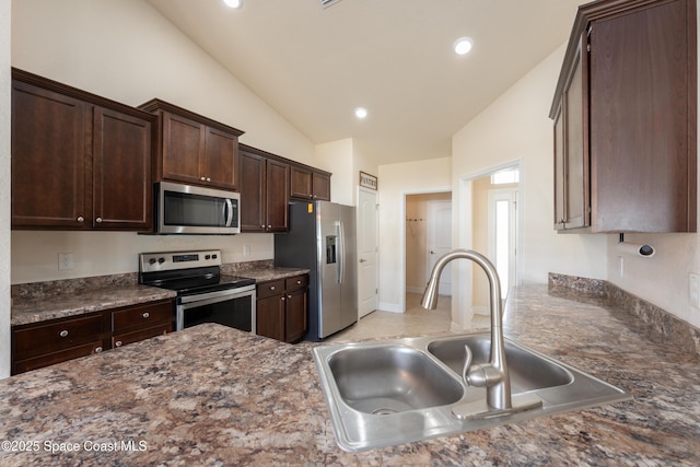 kitchen with recessed lighting, appliances with stainless steel finishes, a sink, dark stone countertops, and dark brown cabinets