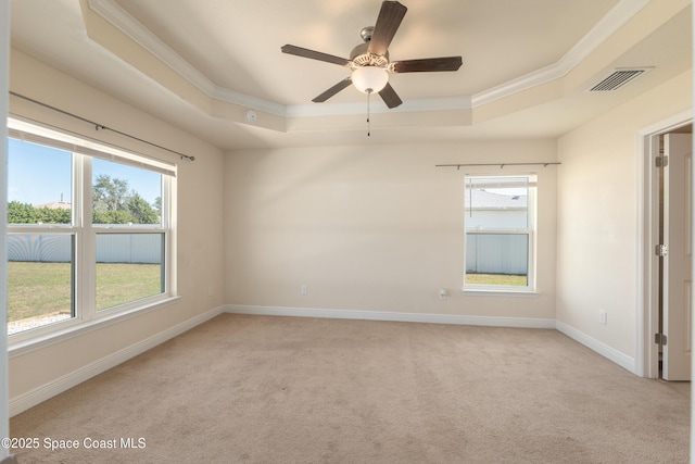 unfurnished room featuring a tray ceiling, crown molding, visible vents, light carpet, and baseboards