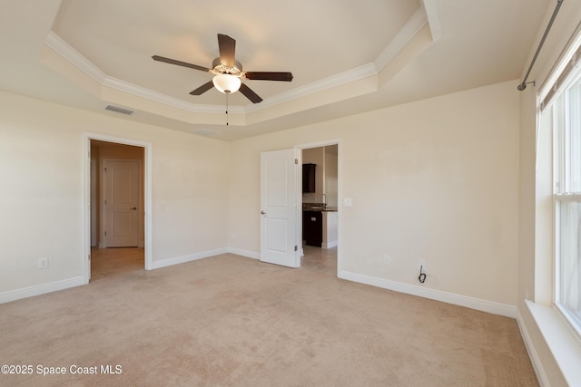 unfurnished bedroom with light carpet, a tray ceiling, visible vents, and crown molding