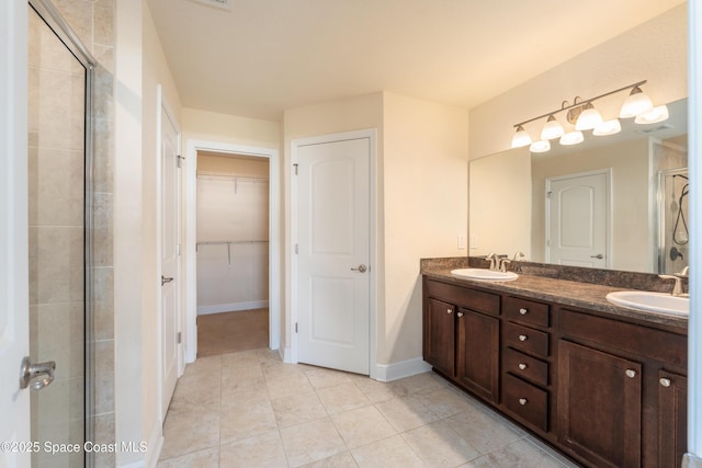 bathroom featuring double vanity, a spacious closet, a stall shower, and a sink