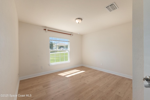 empty room with light wood-style flooring, visible vents, and baseboards