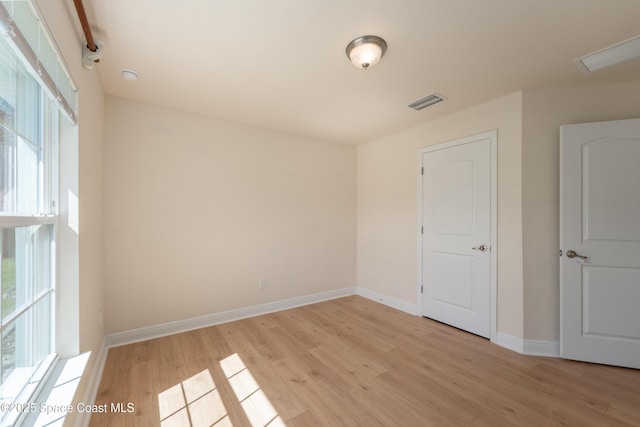 spare room with light wood-style floors, visible vents, and baseboards