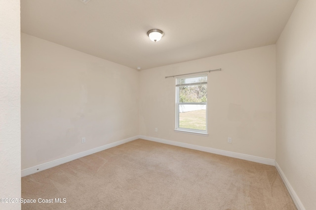 unfurnished room with baseboards and light colored carpet