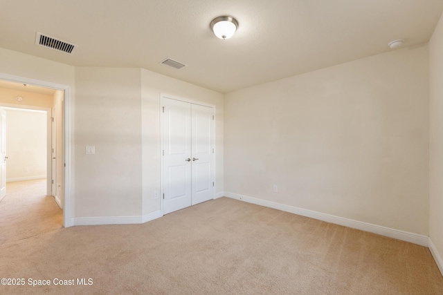 unfurnished bedroom featuring light carpet, a closet, and visible vents