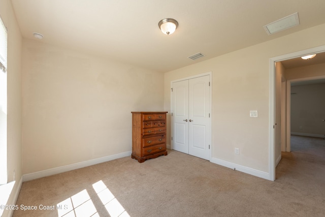 unfurnished bedroom featuring a closet, carpet flooring, visible vents, and baseboards