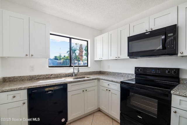 kitchen with light tile patterned floors, a textured ceiling, a sink, white cabinets, and black appliances