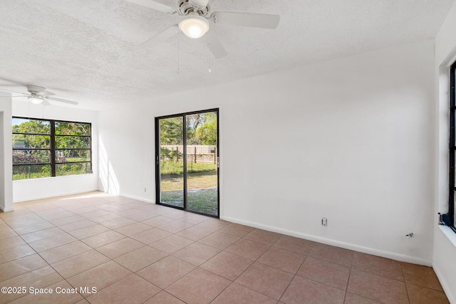 unfurnished room featuring tile patterned flooring, plenty of natural light, a textured ceiling, and baseboards