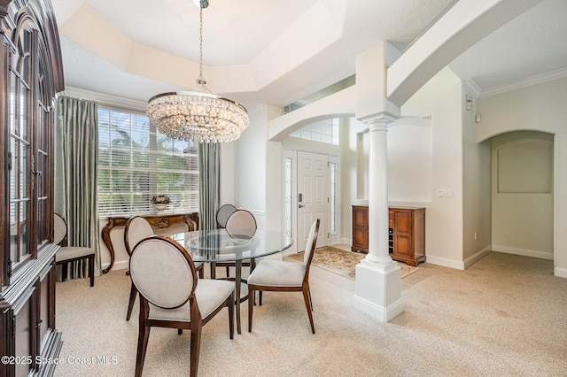 dining space with decorative columns, baseboards, arched walkways, light colored carpet, and a tray ceiling