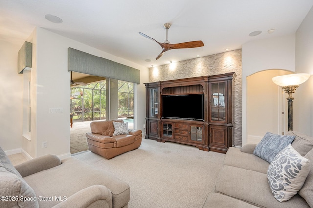 carpeted living area with a sunroom, baseboards, and a ceiling fan