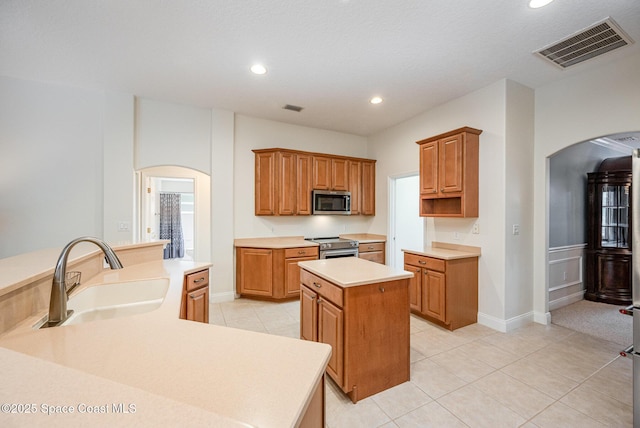 kitchen featuring arched walkways, stainless steel appliances, visible vents, and a center island with sink