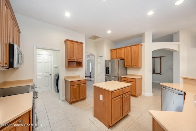 kitchen featuring visible vents, arched walkways, appliances with stainless steel finishes, light countertops, and separate washer and dryer