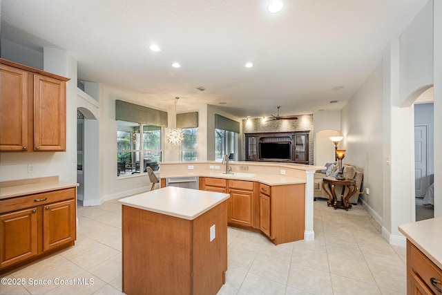 kitchen featuring arched walkways, a kitchen island, open floor plan, light countertops, and dishwasher