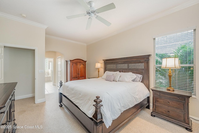 bedroom featuring arched walkways, ensuite bathroom, light colored carpet, baseboards, and crown molding