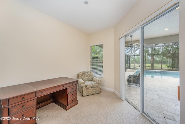 office area featuring a sunroom, light colored carpet, ceiling fan, and baseboards