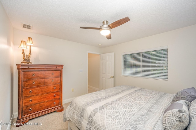 carpeted bedroom featuring a textured ceiling, a ceiling fan, visible vents, and baseboards