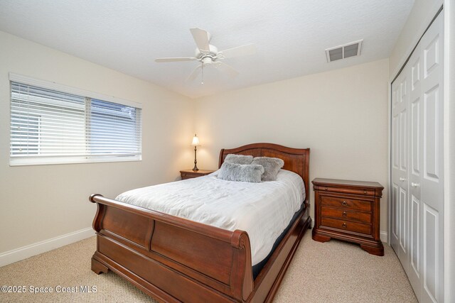 bedroom featuring a closet, visible vents, light carpet, ceiling fan, and baseboards