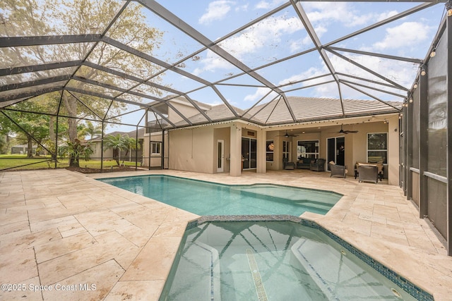 view of swimming pool with a patio area, a lanai, a pool with connected hot tub, and a ceiling fan