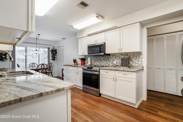 kitchen featuring white cabinets, visible vents, stainless steel appliances, and a sink