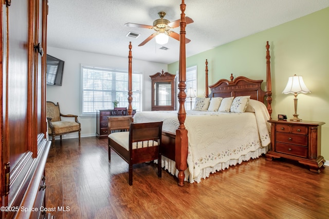 bedroom featuring a textured ceiling, wood finished floors, visible vents, and baseboards