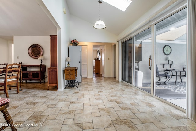 foyer with high vaulted ceiling, a skylight, and baseboards